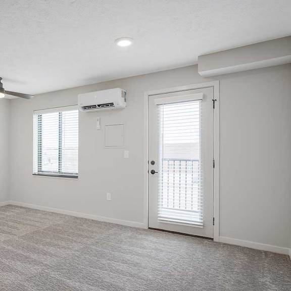 Thumbnail 8 of 25 a main room with a ceiling fan, mounted A/C, and a door to the balcony
