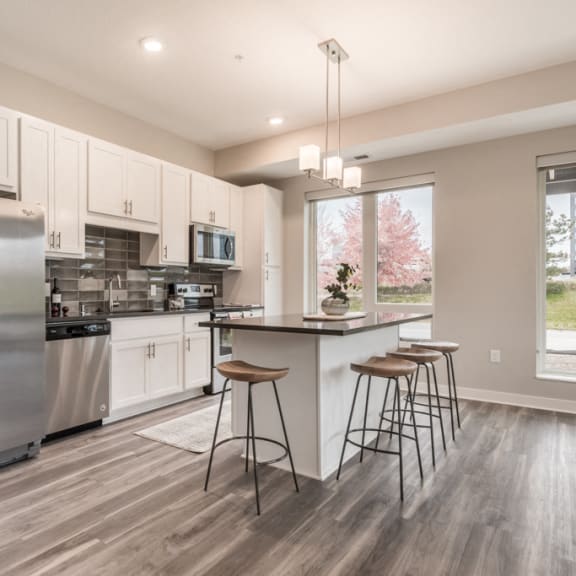 Thumbnail 6 of 18 kitchen with white cabinets, dark gray counters and stainless steel appliances. includes island with bar stools