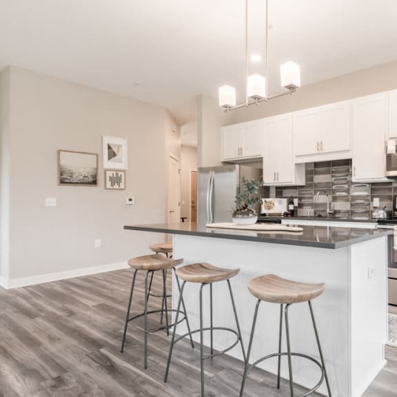 Thumbnail 8 of 18 kitchen with white cabinets, dark gray counters and stainless steel appliances. includes island with bar stools