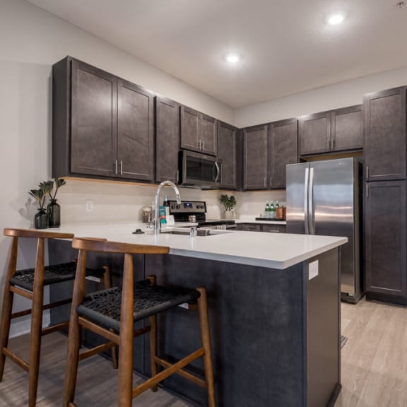 Thumbnail 5 of 13 U-shaped kitchen with dark brown cabinets, stainless appliances, and white counters