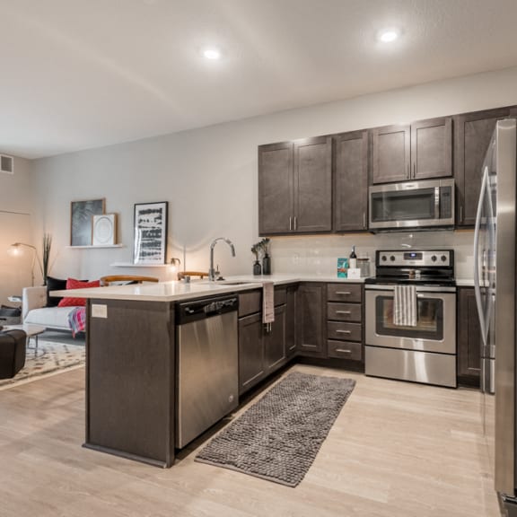 Thumbnail 4 of 13 U-shaped kitchen with dark brown cabinets, stainless appliances, and white counters