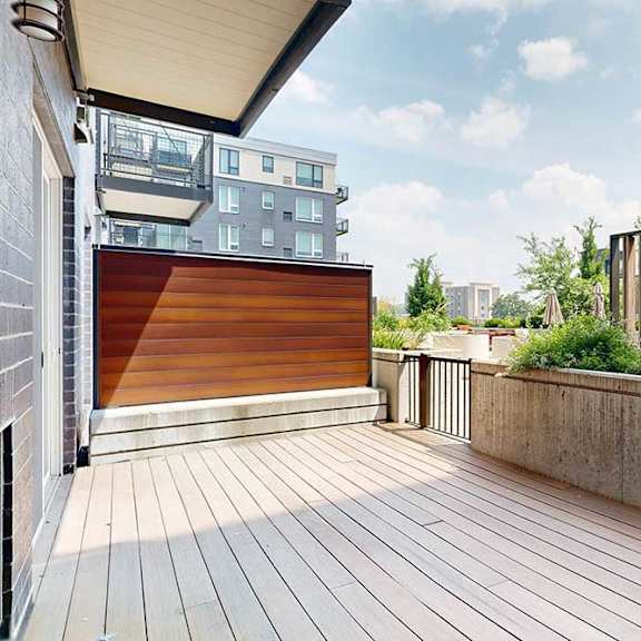 Thumbnail 15 of 31 A patio with a wooden deck and wooden privacy wall.