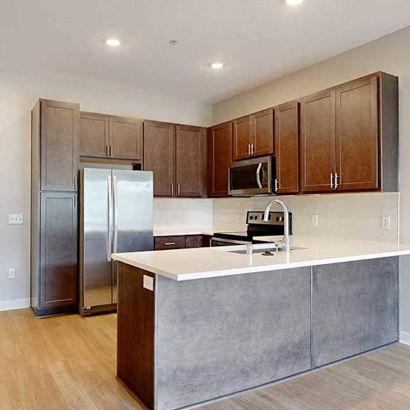 Thumbnail 7 of 31 A modern kitchen with dark wooden cabinets, quartz countertops, and stainless steel appliances.