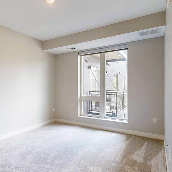 Thumbnail 16 of 22 A carpeted bedroom with a floor-to-ceiling window.