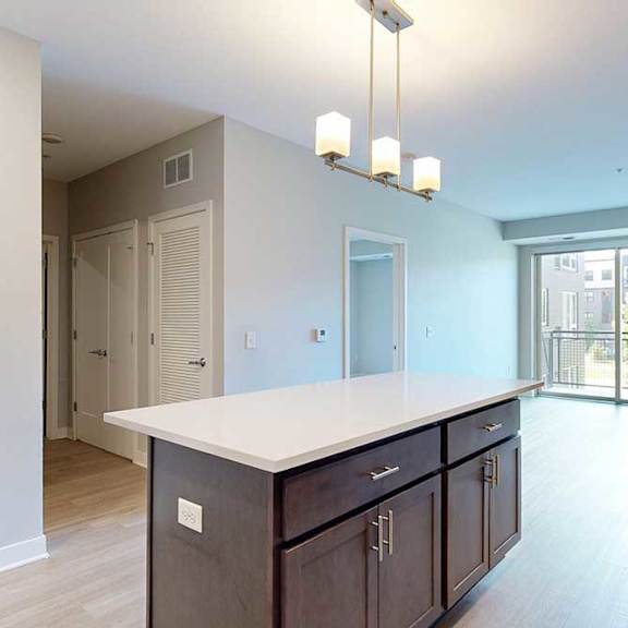 Thumbnail 7 of 22 A kitchen with dark wood cabinets and a large island in front of a spacious living room.