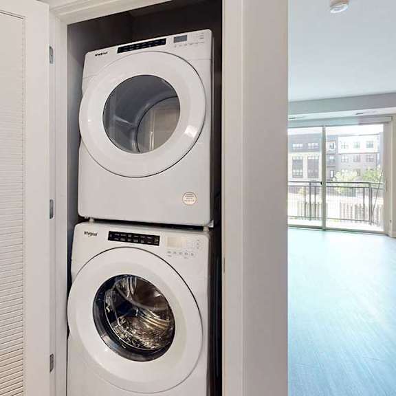 Thumbnail 9 of 22 A stacked full-sized washer and dryer in a laundry closet.