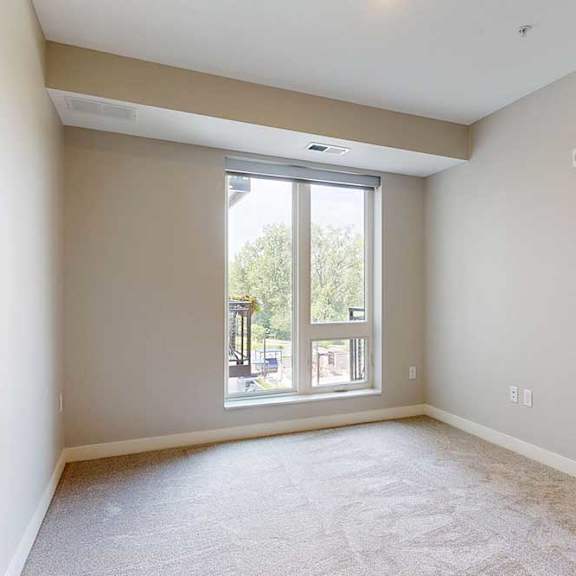 Thumbnail 18 of 25 A carpeted bedroom with a floor-to-ceiling window.
