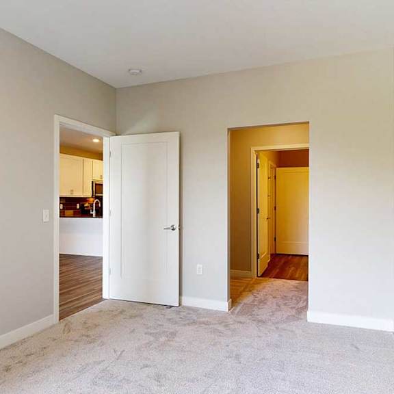 Thumbnail 17 of 25 A carpeted bedroom with an attached walk-through closet connected to a bathroom.