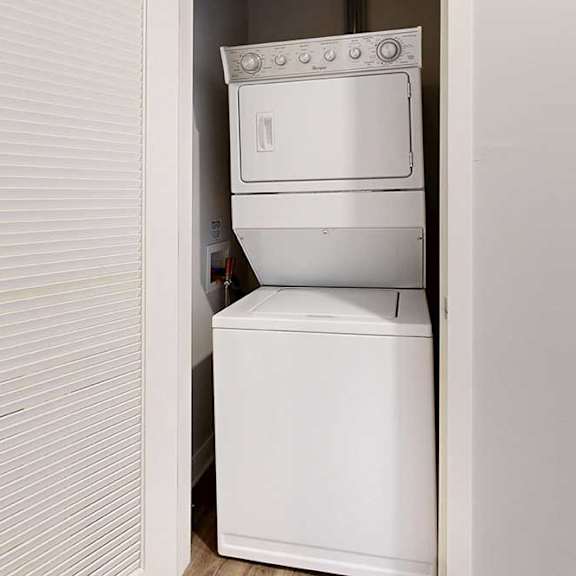 Thumbnail 25 of 25 A stacked full-sized washer and dryer in a laundry closet.