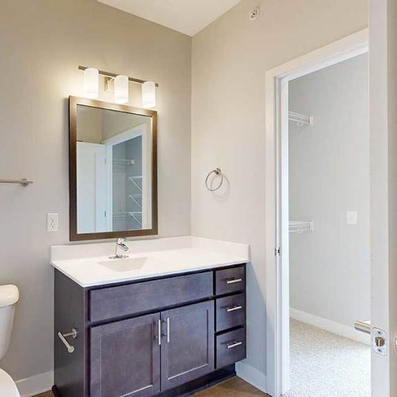 Thumbnail 23 of 27 A bathroom with a marble vanity, dark wooden cabinets, connected to a walk-through closet.