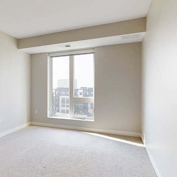 Thumbnail 20 of 27 A carpeted bedroom with a floor-to-ceiling window.