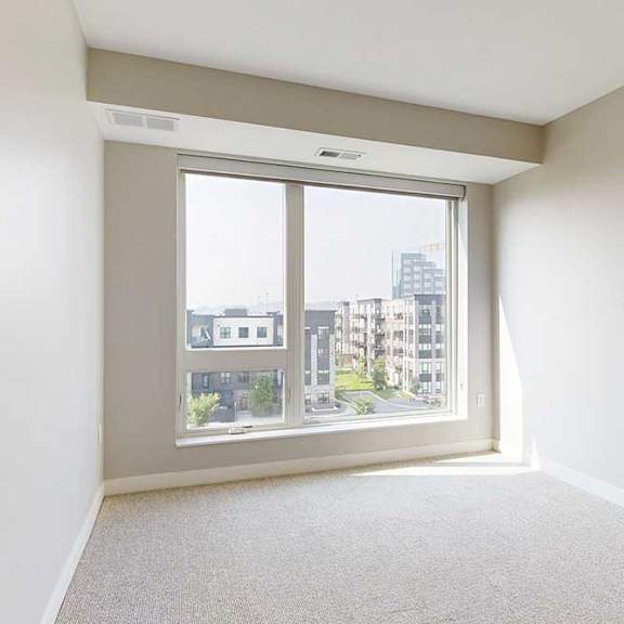Thumbnail 14 of 27 A carpeted bedroom with a floor-to-ceiling window.