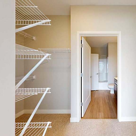 Thumbnail 22 of 27 An oversized walk-in closet with several built-in wire shelves, connected to a bathroom.