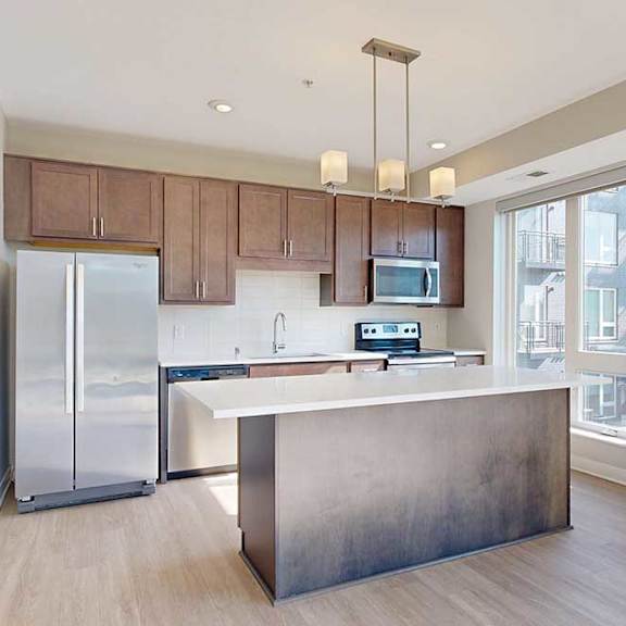 Thumbnail 13 of 27 A kitchen with dark wood cabinets, quartz countertops, a large island, stainless steel appliances, and a designer backsplash.