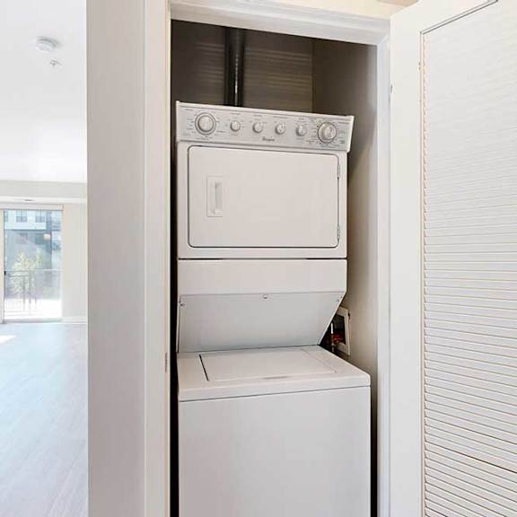 Thumbnail 6 of 27 A stacked full-sized washer and dryer in a laundry closet.