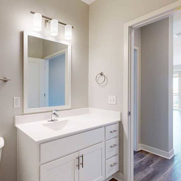 Thumbnail 28 of 29 A bathroom with a marble vanity, white wooden cabinets, and a mirror with overhead lighting.