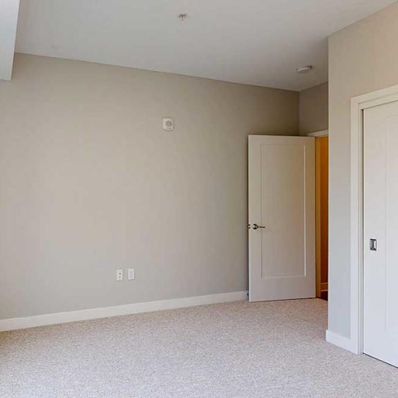 Thumbnail 25 of 29 A carpeted bedroom with a floor-to-ceiling window and a sliding-door closet.