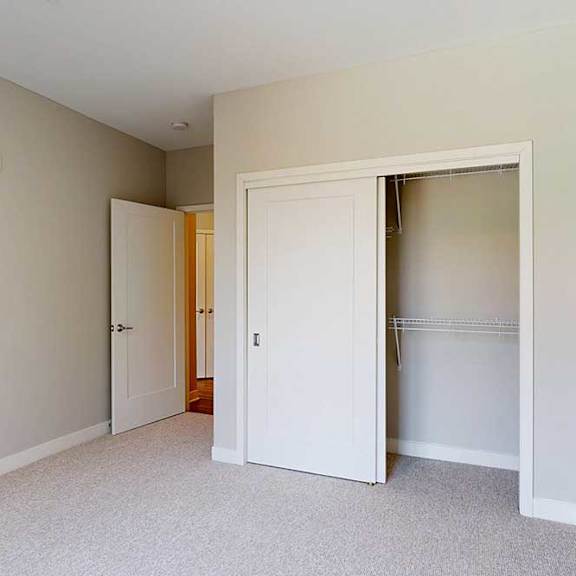Thumbnail 24 of 29 A carpeted bedroom with a sliding-door closet.
