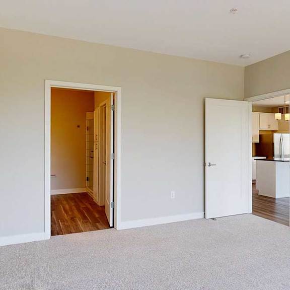 Thumbnail 15 of 29 A carpeted bedroom with an attached bathroom and a door open to the living room.