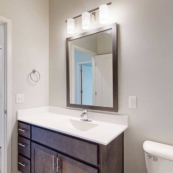 Thumbnail 28 of 29 A bathroom with a marble vanity, dark wooden cabinets, and a mirror with overhead lighting.