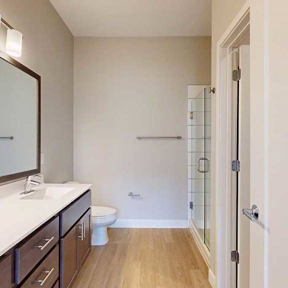 Thumbnail 20 of 29 A bathroom with a marble vanity, dark wooden cabinets, and a walk-in shower.