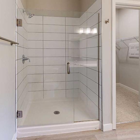 Thumbnail 22 of 29 A bathroom with a tiled walk-in shower with a glass door.