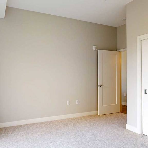 Thumbnail 25 of 29 A carpeted bedroom with a floor-to-ceiling window and sliding-door closet.
