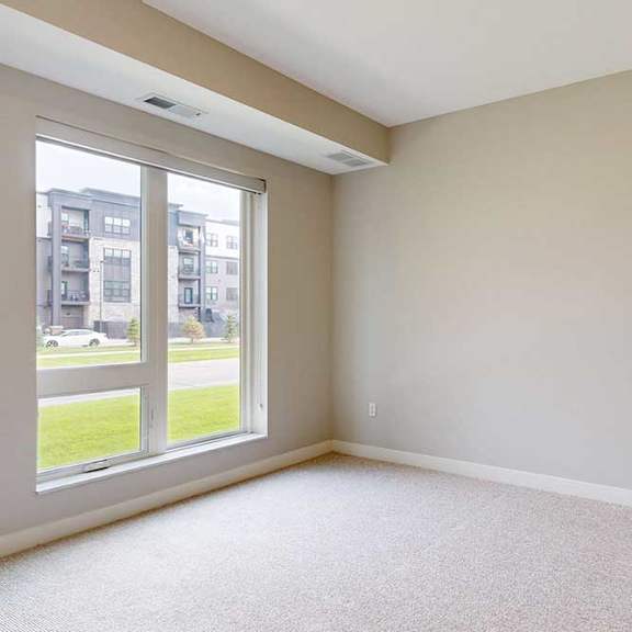 Thumbnail 19 of 29 A carpeted bedroom with a floor-to-ceiling window.
