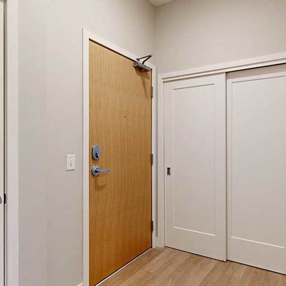 Thumbnail 4 of 29 A front entryway with a wooden front door and a sliding door coat closet.