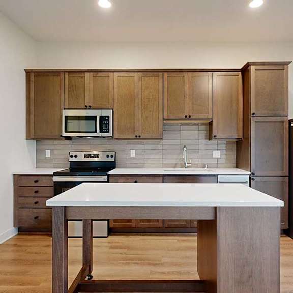 Thumbnail 12 of 16 A kitchen with a moveable island and brown wood cabinets.