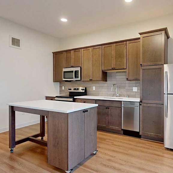 Thumbnail 11 of 16 A kitchen with a white counter top and a stainless steel refrigerator.