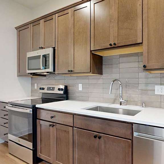 Thumbnail 7 of 16 A kitchen with brown cabinets and a white countertop.