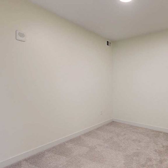 Thumbnail 4 of 17 A room with a carpeted floor and white walls.