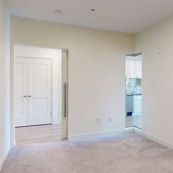 Thumbnail 5 of 17 Carpeted sleeping area with pocket door and corner window looking to ktichen