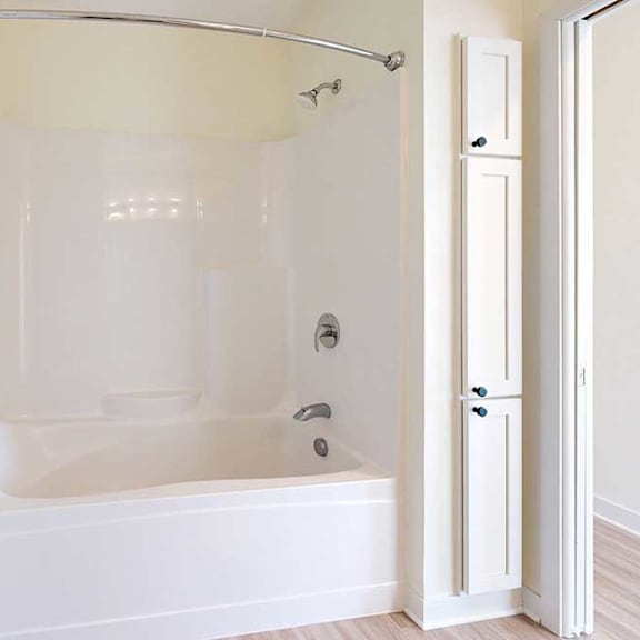 Thumbnail 23 of 23 A clean, white bathroom featuring a bathtub with a shower, a curved curtain rod, and adjacent storage cabinets.