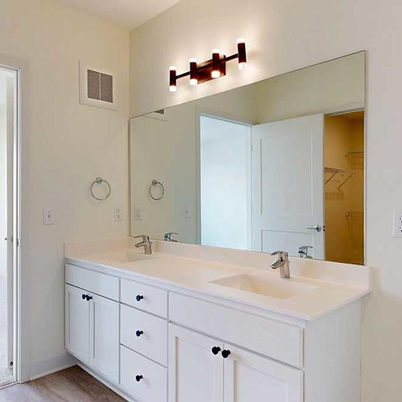 Thumbnail 16 of 23 Modern bathroom with a large mirror, double sinks, white cabinetry, and overhead lighting. Neutral tones create a clean and spacious feel.