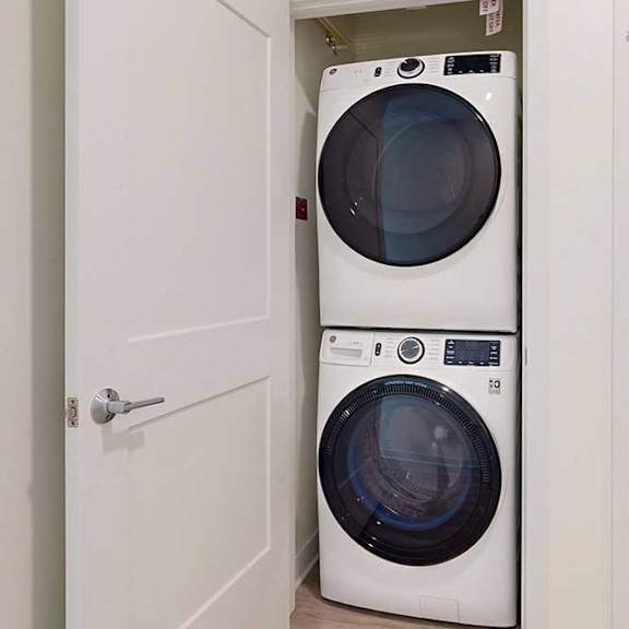 Thumbnail 4 of 23 A white washing machine is in a small space between two doors.