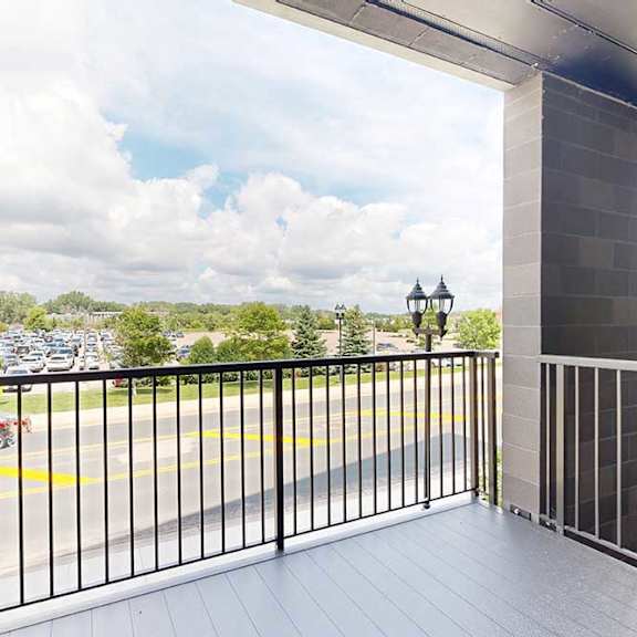 Thumbnail 19 of 31 A balcony with a view of a parking lot and trees.