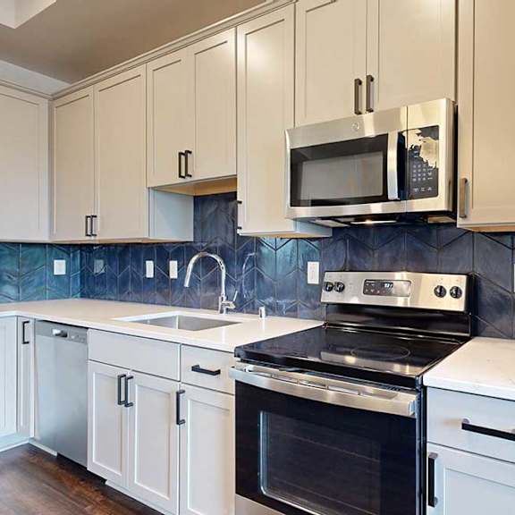 Thumbnail 5 of 31 A kitchen with white cabinets and stainless steel appliances