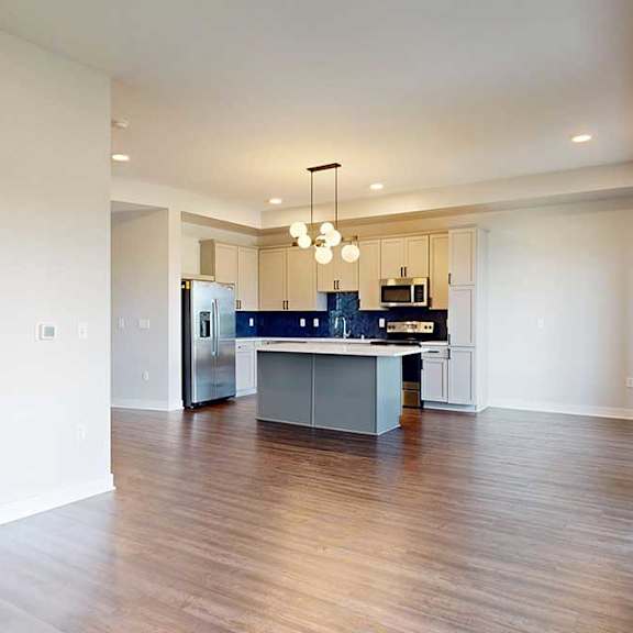 Thumbnail 11 of 31 A spacious kitchen and living room area with a center island and pendant lights.