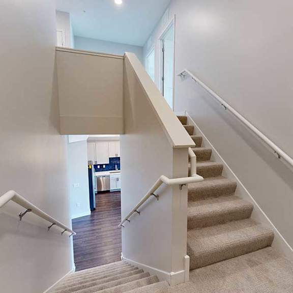 Thumbnail 17 of 31 A staircase with a beige carpet and white railings.