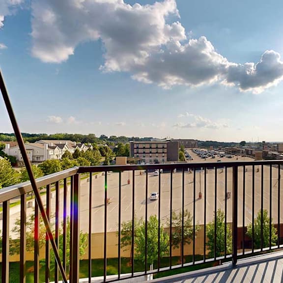 Thumbnail 11 of 19 A balcony overlooks a cityscape with buildings and greenery.