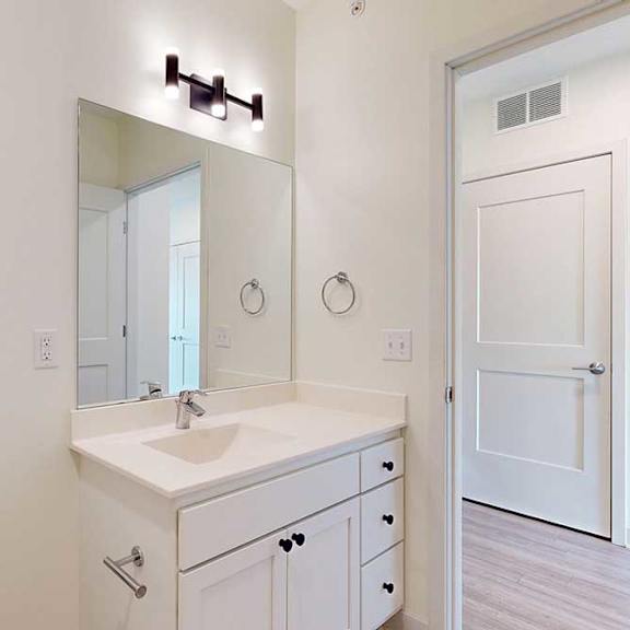 Thumbnail 19 of 19 Modern bathroom with a clean, minimalist design. Features a large mirror, white vanity, sink, and a toilet.