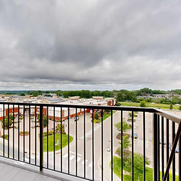 Thumbnail 16 of 26 A balcony overlooks a parking lot and buildings.