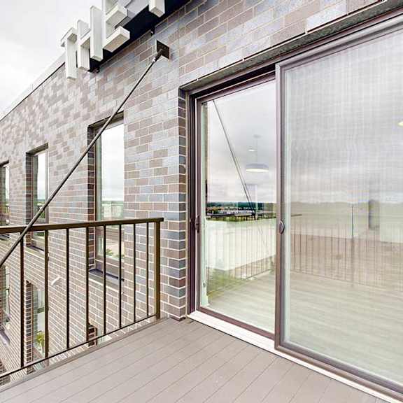 Thumbnail 17 of 26 A balcony with a glass door and a metal railing.