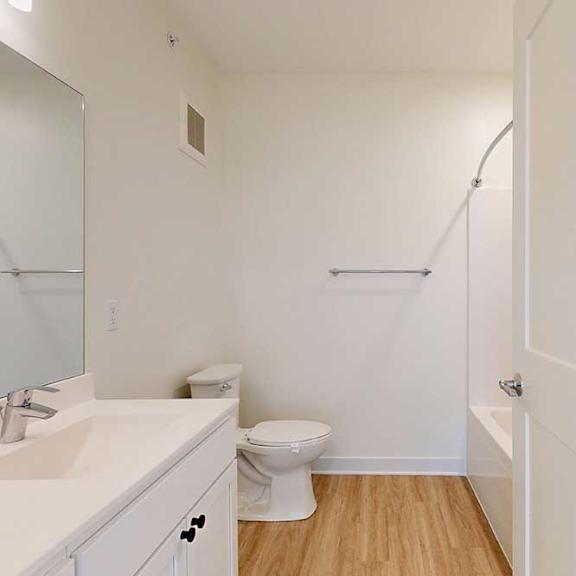 Thumbnail 5 of 26 A white bathroom with a toilet, sink, and a shower.