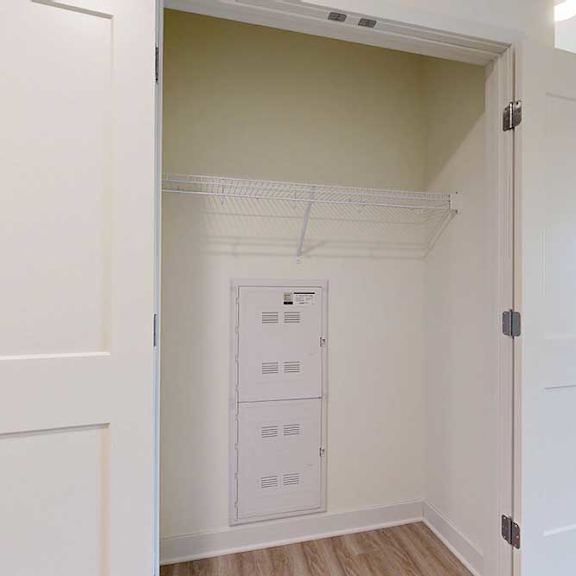 Thumbnail 4 of 26 A white door is open to a hall closet with a white wall and a white shelf.
