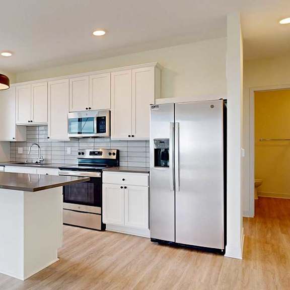 Thumbnail 10 of 26 A modern kitchen with white cabinets and stainless steel appliances.