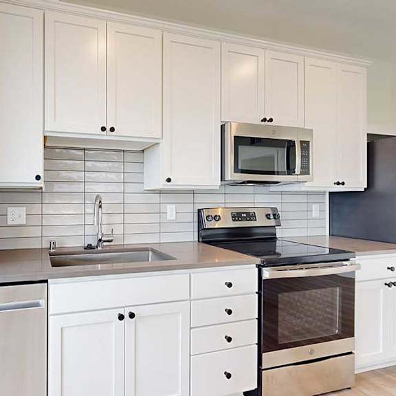 Thumbnail 12 of 26 A kitchen with white cabinets and stainless steel appliances.