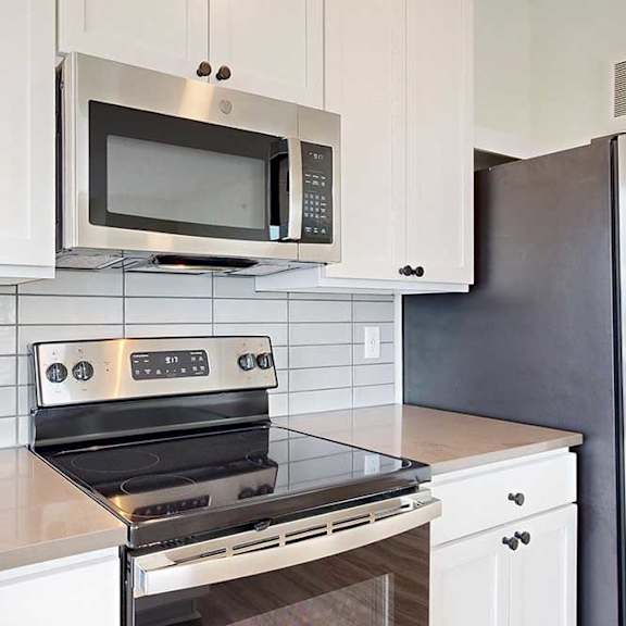 Thumbnail 13 of 26 A modern kitchen with a stainless steel oven and microwave above it.
